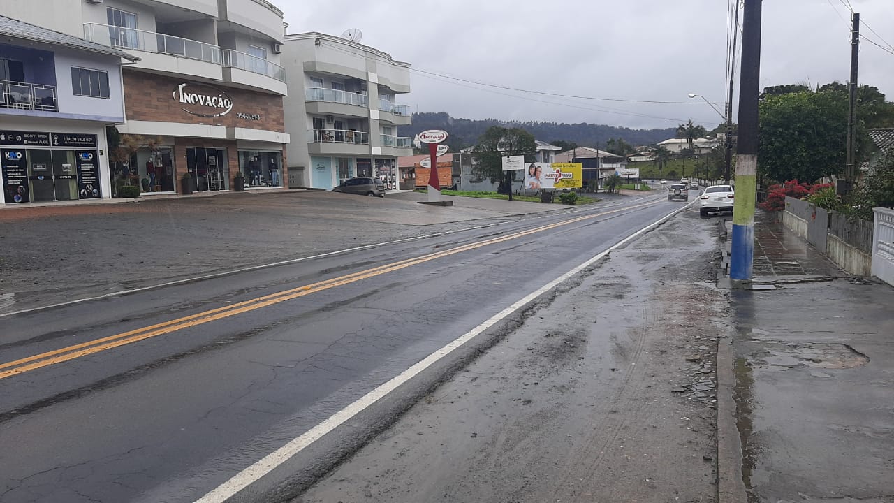 Rua comercial de Trombudo Central (SC) em dia chuvoso, com movimento local