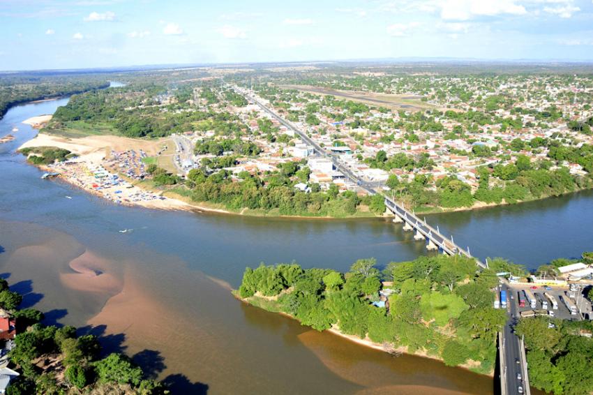 Praia fluvial de Luiz Alves, em São Miguel do Araguaia GO, com barrancas de areia e embarcações ao fundo sob céu azul