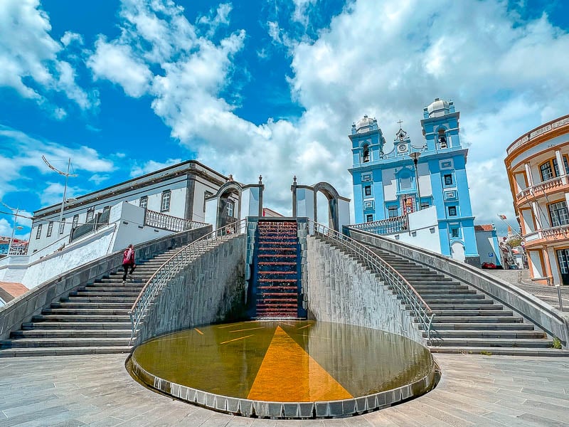 Praça central com igreja e casario colorido sob céu azul