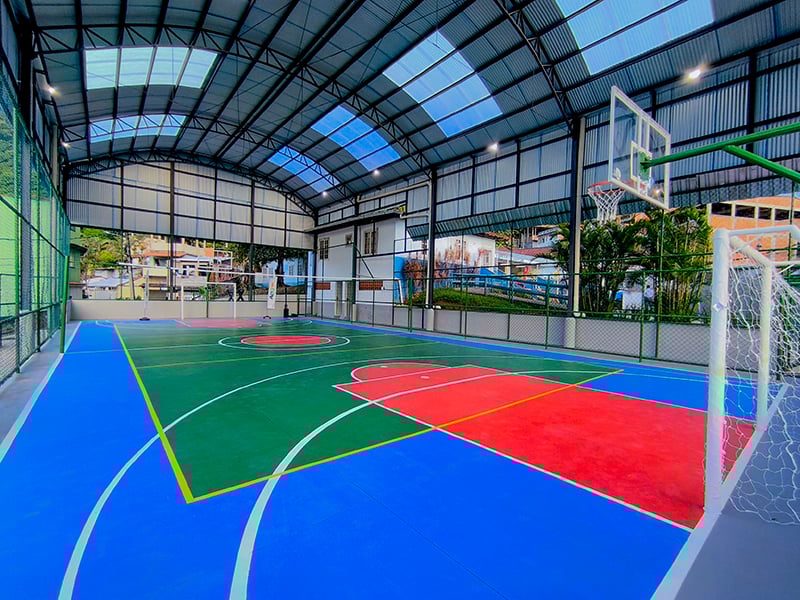 Quadra poliesportiva coberta com cestos de basquete, espaço de uso comunitário