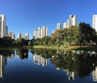 Parque Flamboyant em Goiânia ao entardecer, com lago e prédios ao fundo