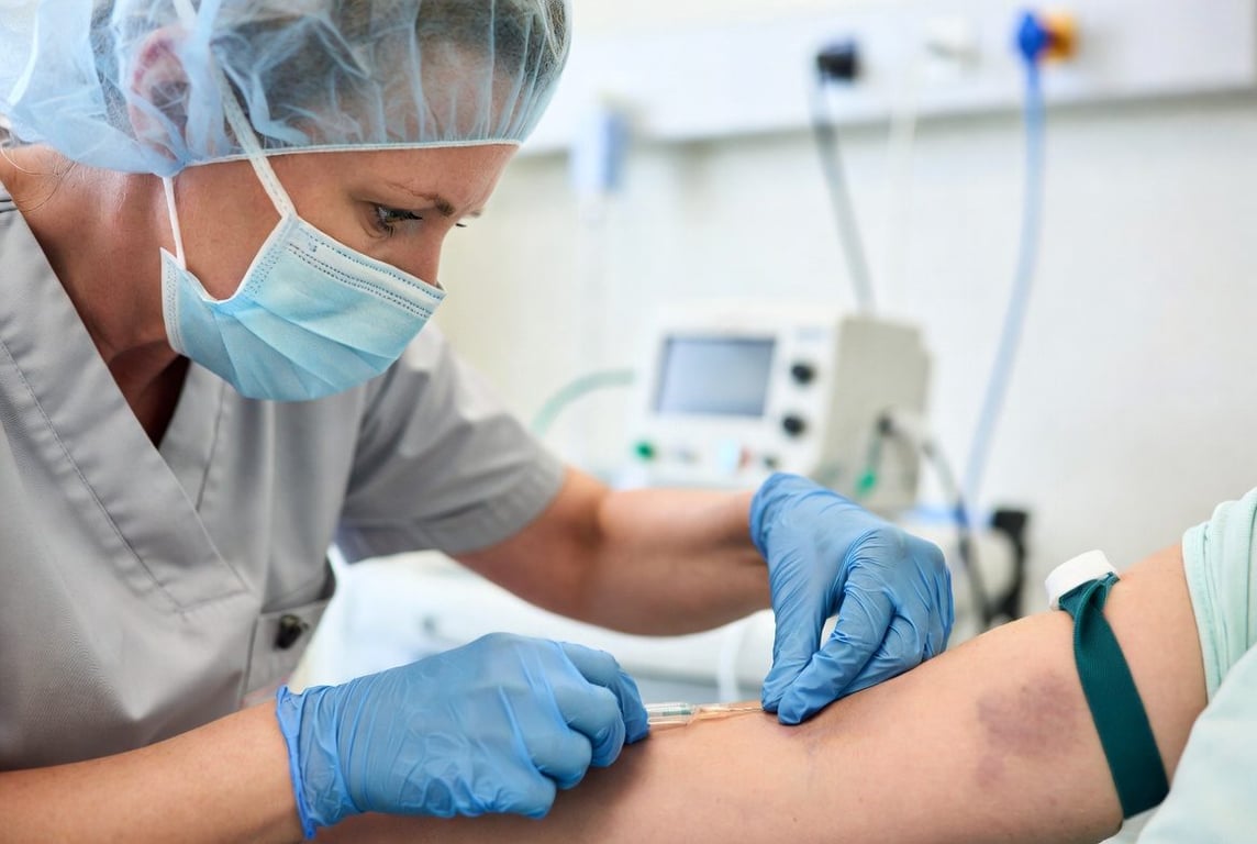 Profissional técnico de enfermagem em ambiente clínico, com foco nas mãos e materiais de enfermagem