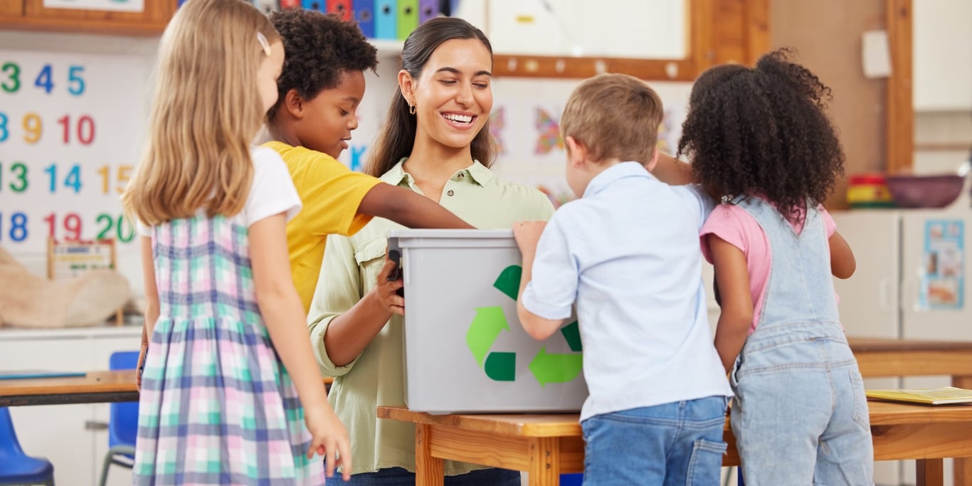 Cena de uma professora interagindo com crianças em sala de aula, em clima de aprendizado e acolhimento