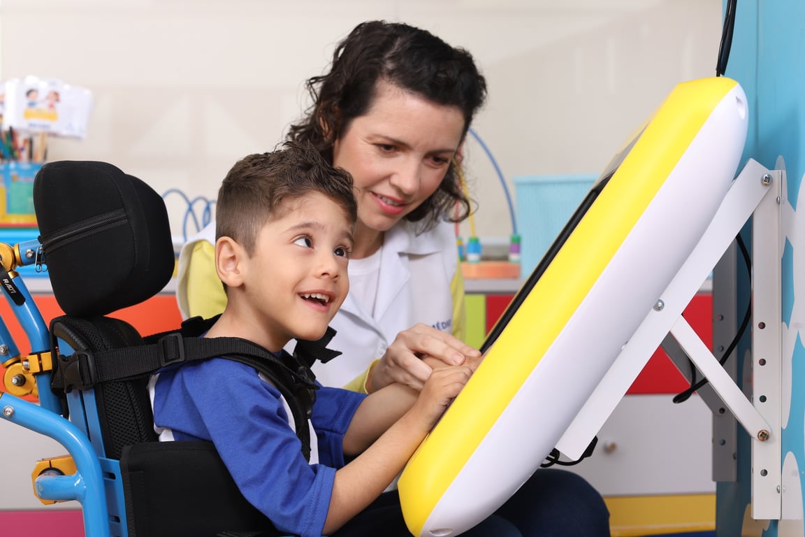 Professor de apoio interagindo com estudante em sala inclusiva