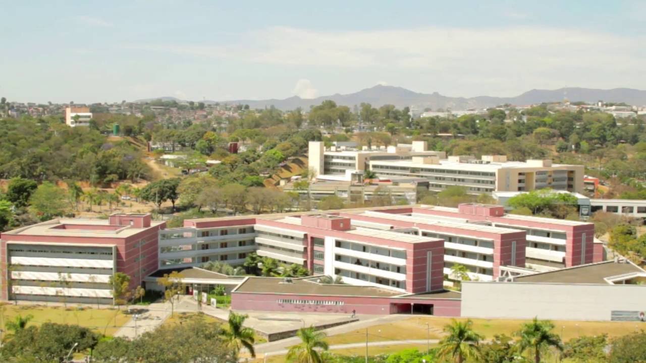 Campus Pampulha da UFMG ao entardecer, com prédios e área verde