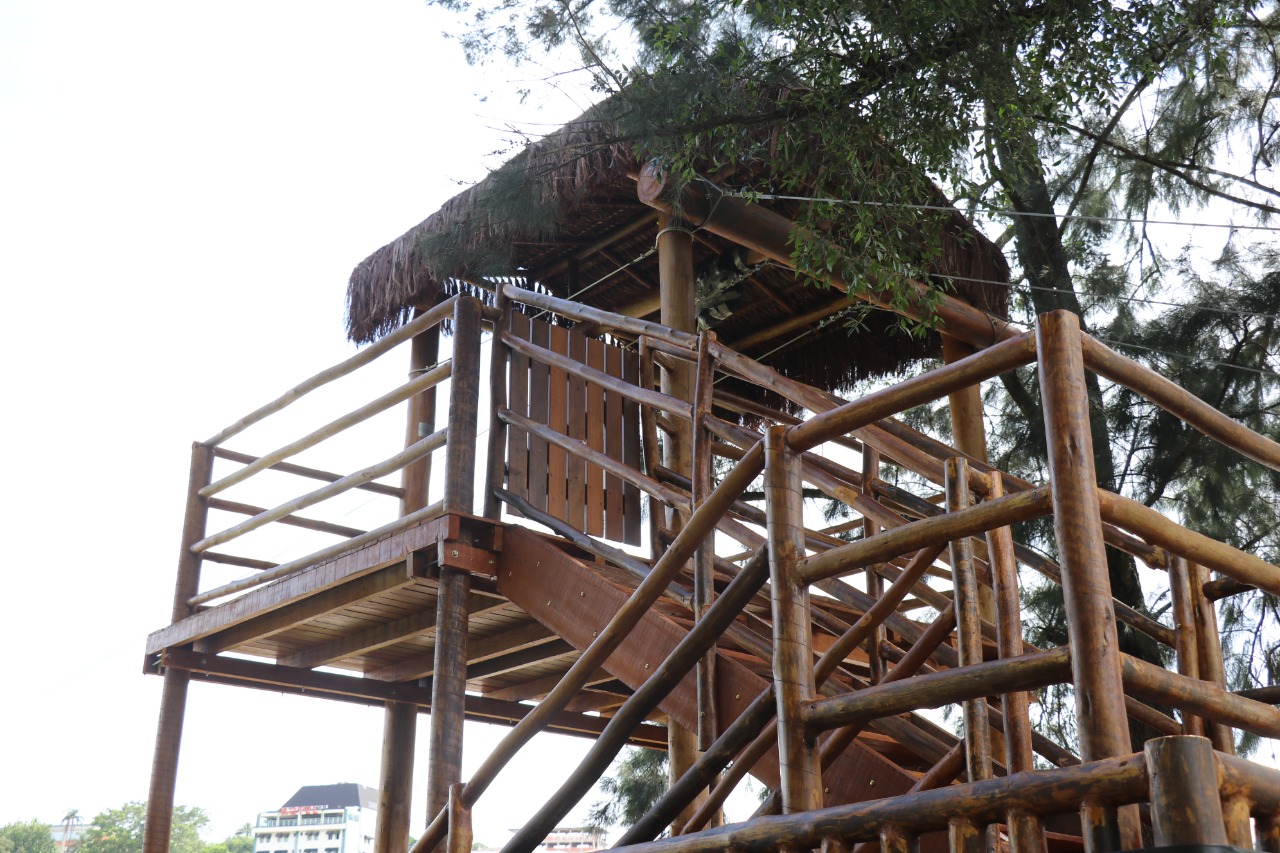 Estrutura de madeira tipo mirante em área arborizada, luz suave da manhã, composição horizontal