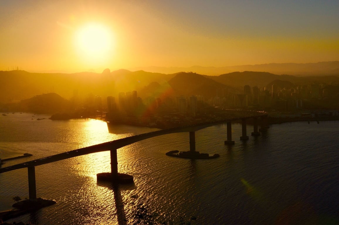 Vista da orla de Vitória ao pôr do sol, com a Terceira Ponte ao fundo