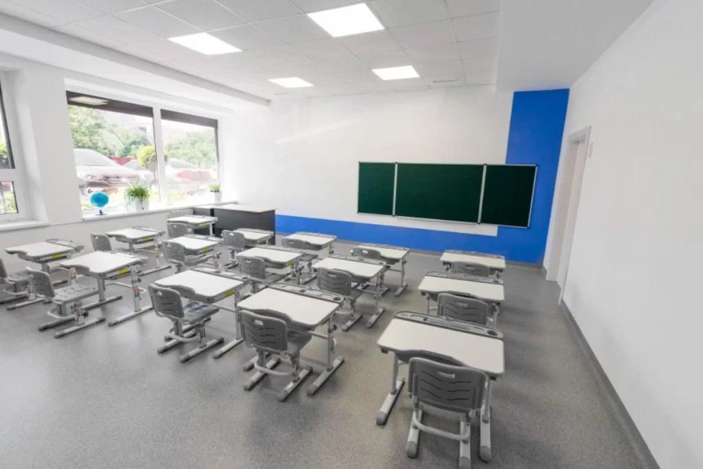 Sala de aula do ensino fundamental com carteiras e lousa, ambiente simples e iluminado naturalmente