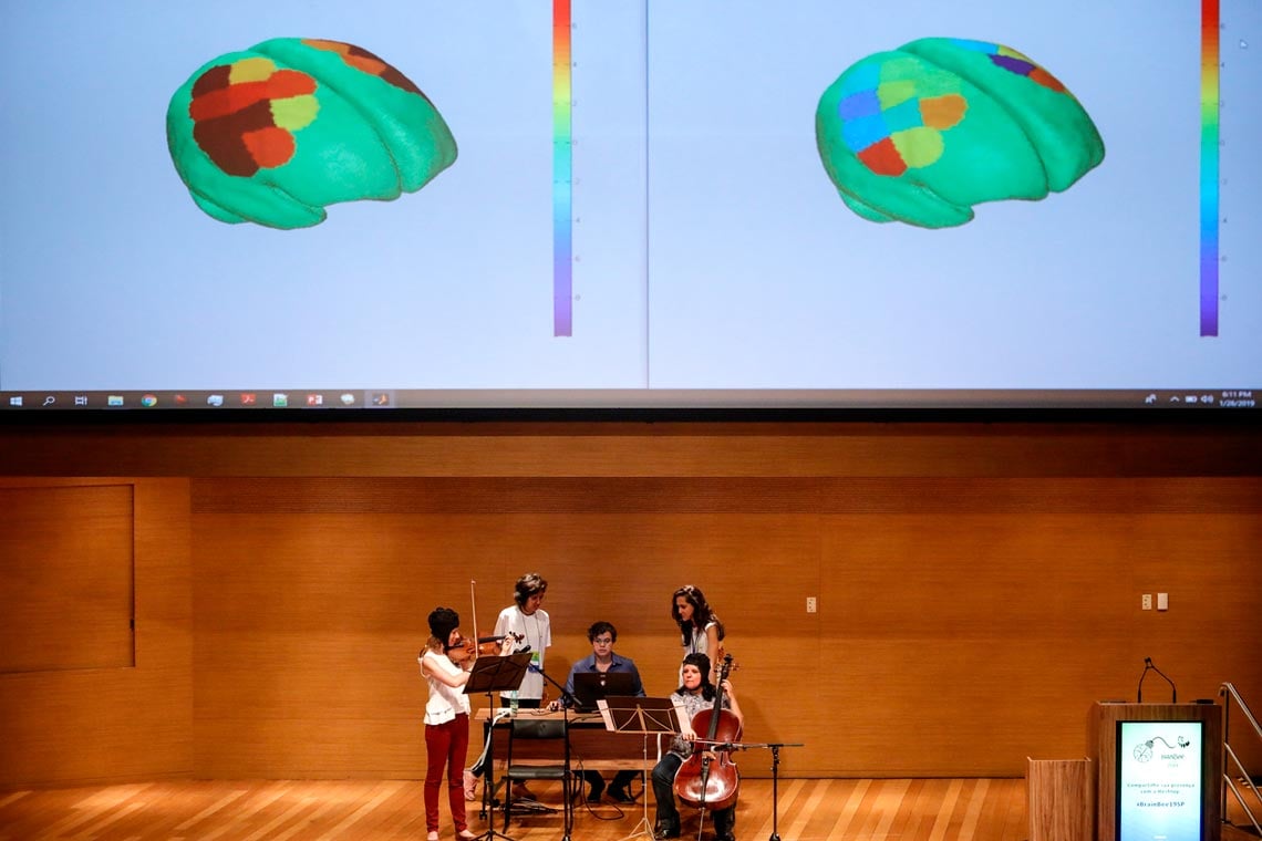 Docente ministrando aula com imagens do cérebro projetadas em telão