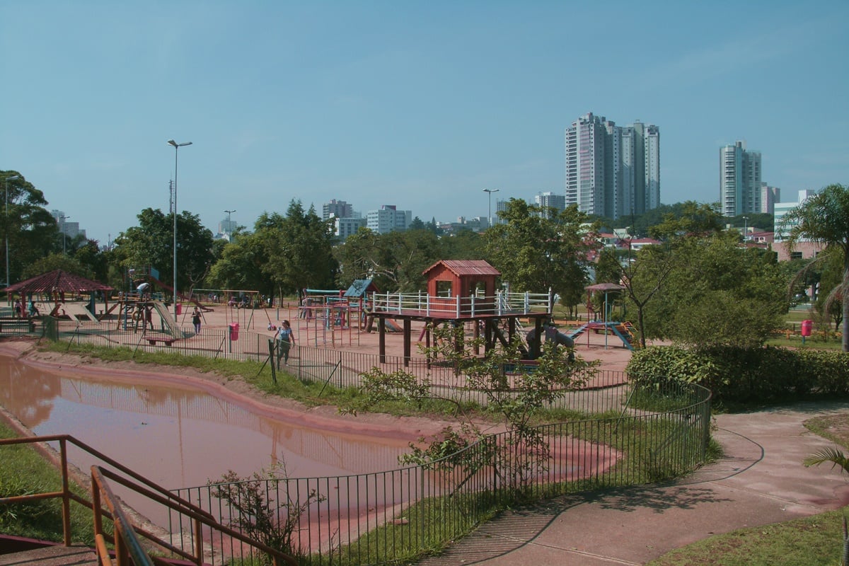 Parque urbano em Guarulhos, com lago e área de lazer em dia ensolarado