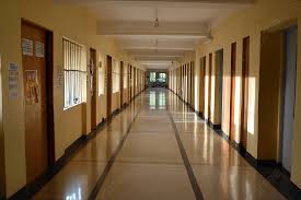 Corredor amplo e iluminado de instituição de ensino superior, com portas ao longo do trajeto.