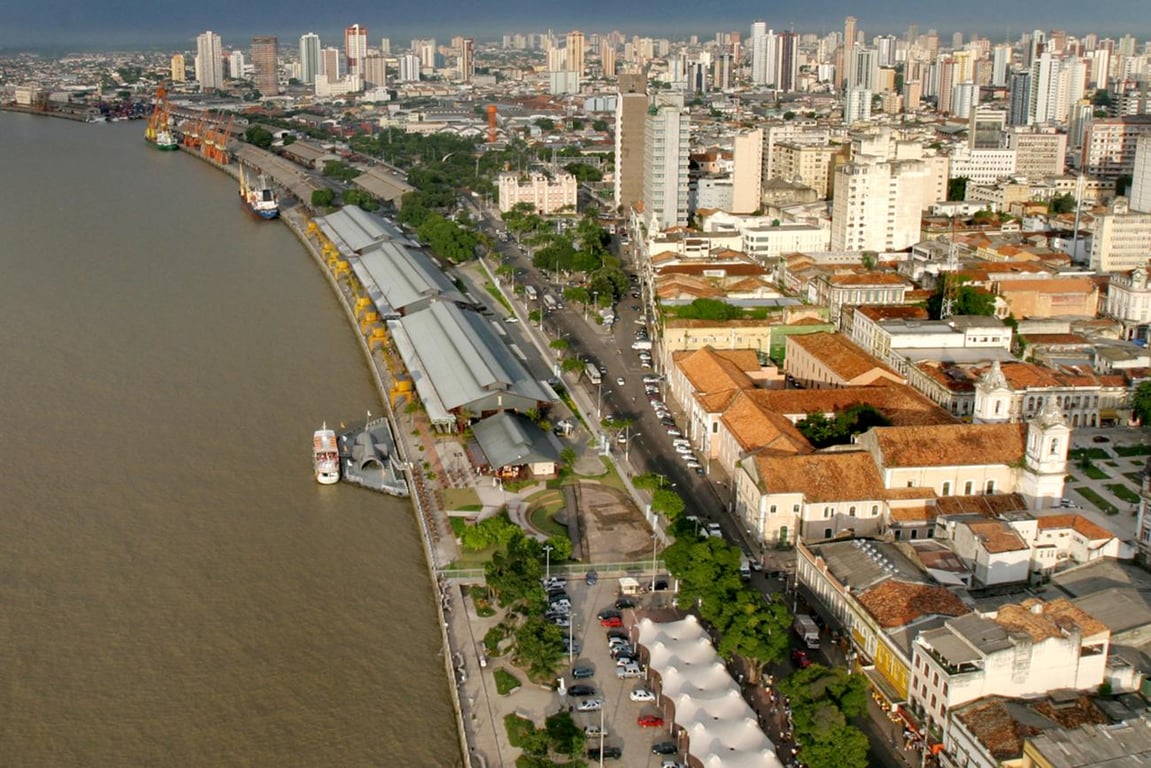 Vista aérea de Belém do Pará ao entardecer, com rio e skyline ao fundo
