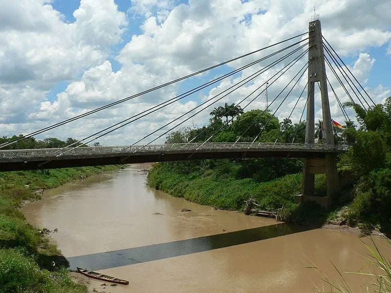 Ponte sobre rio em área urbana, céu azul e vegetação — paisagem de referência do Alto Acre