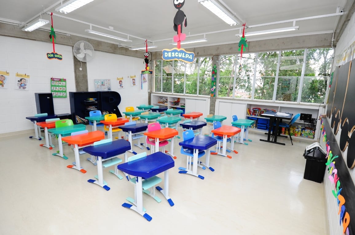 Ambiente de educação infantil com mesas e brinquedos, iluminado por luz natural