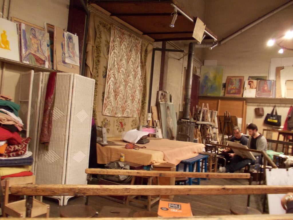 Ateliê de artes acadêmico, com cavaletes, telas e luz natural