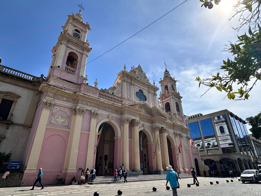 Fachada da Catedral de São Carlos, com céu azul e movimento de pedestres no entorno urbano
