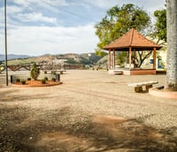 Paisagem urbana de uma praça central em cidade do Oeste Catarinense, com árvores e um gazebô, em dia ensolarado.
