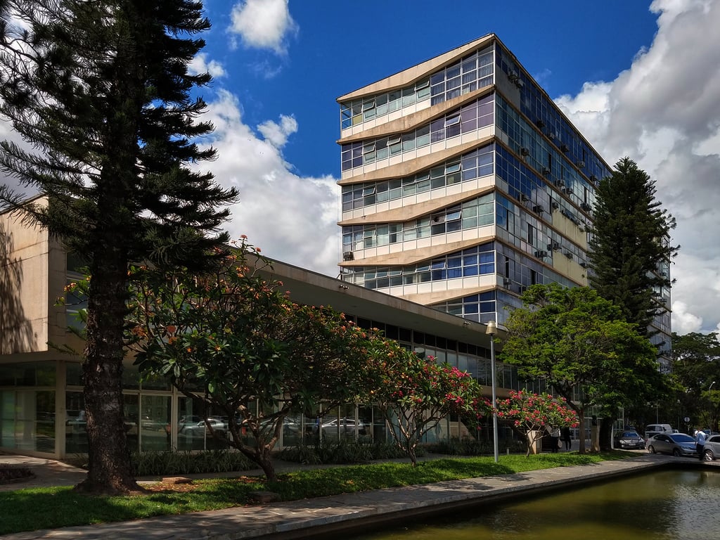 Prédio moderno no campus da UFMG, em Belo Horizonte, com jardim e céu azul