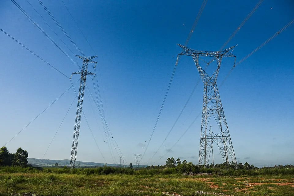 Paisagem rural gaúcha ao entardecer, com campo aberto e torres de transmissão ao fundo