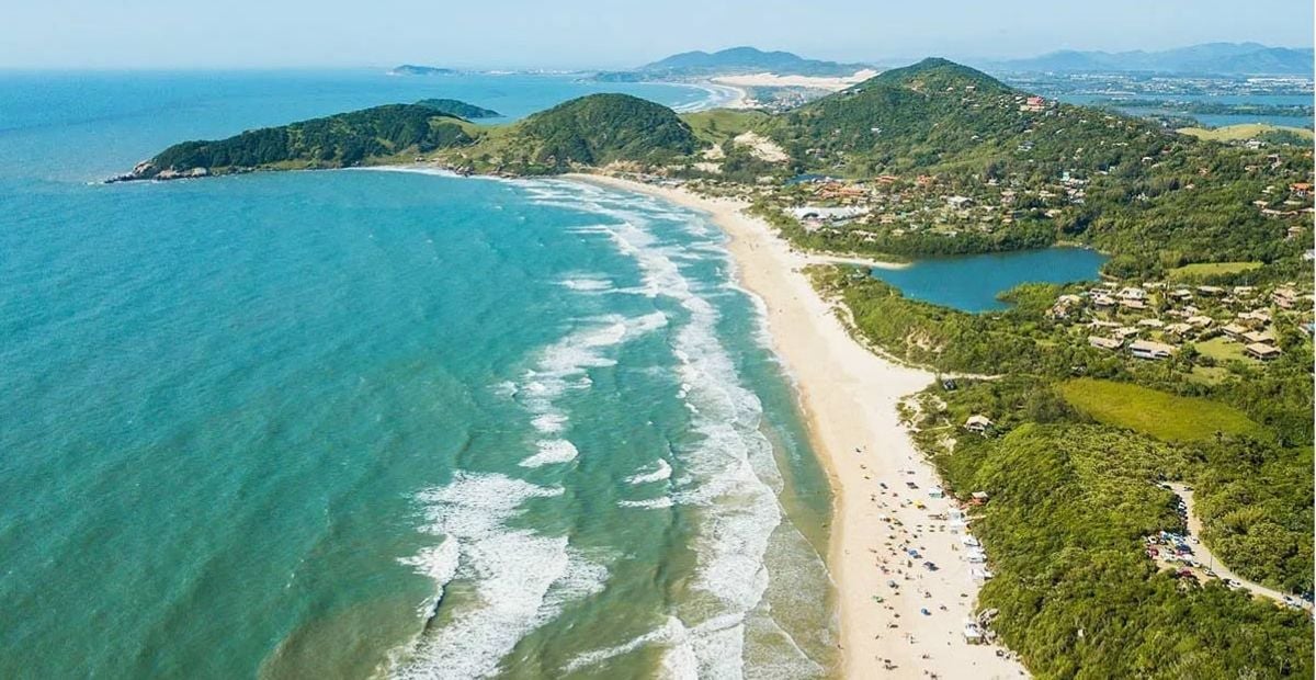 Vista aérea da orla de Imbituba SC, com mar e vegetação ao fundo