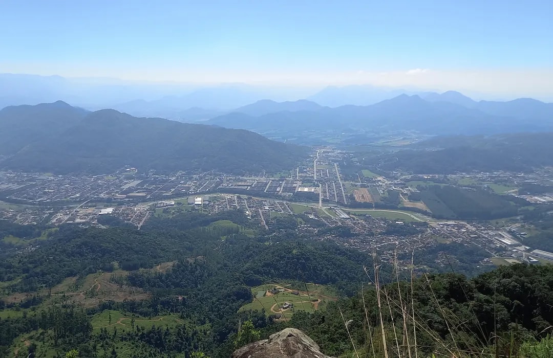 Vista panorâmica de Guaramirim SC ao entardecer, com áreas urbanas e verdes ao fundo
