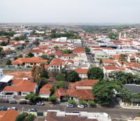 Vista aérea do centro de Itápolis SP ao entardecer, com prédios baixos e casas de telhados vermelhos.
