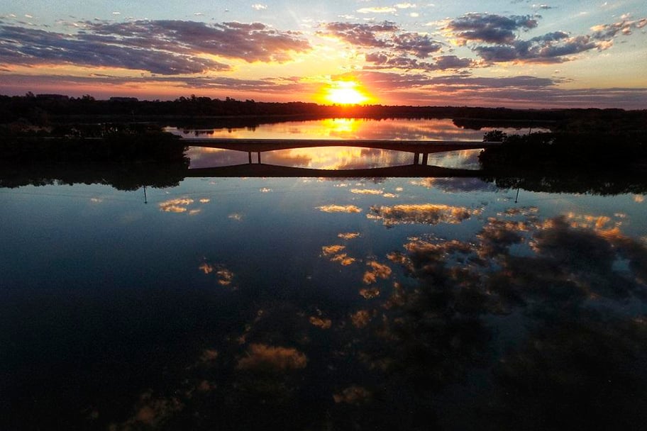 Vista de pequena cidade com rio e morros ao fundo, evocando o cenário do Alto Vale do Itajaí, em Santa Catarina