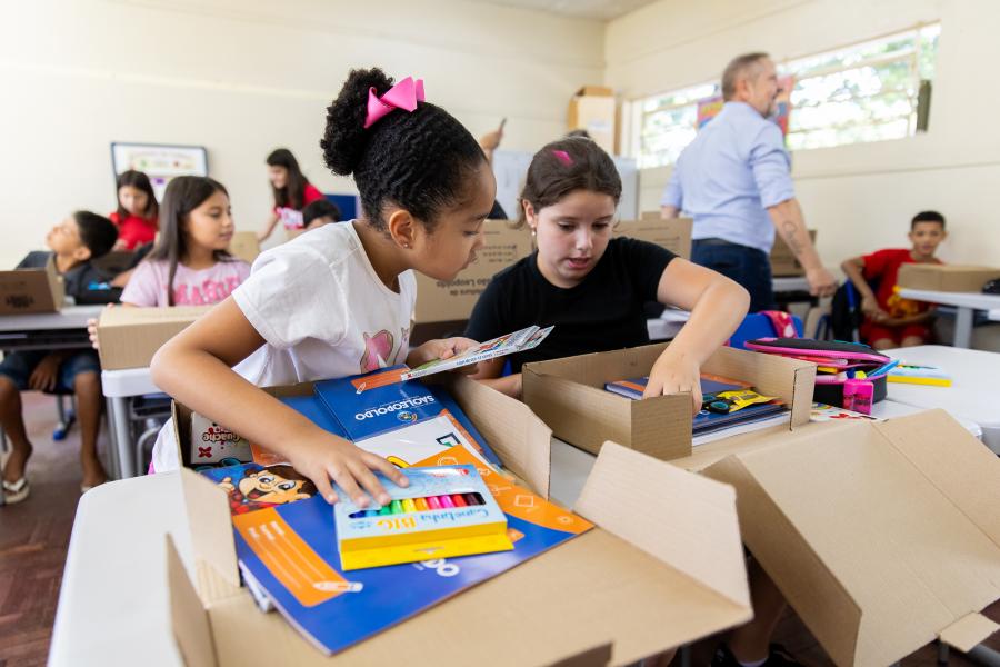 Sala de aula da rede pública com crianças e professor ao fundo