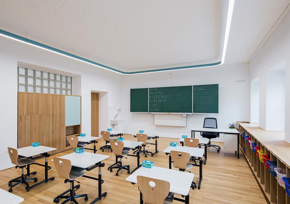 Sala de aula moderna, com carteiras organizadas e iluminação natural.