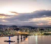 Vista aérea de Vitória, Espírito Santo, ao entardecer, com baía e Terceira Ponte ao fundo.