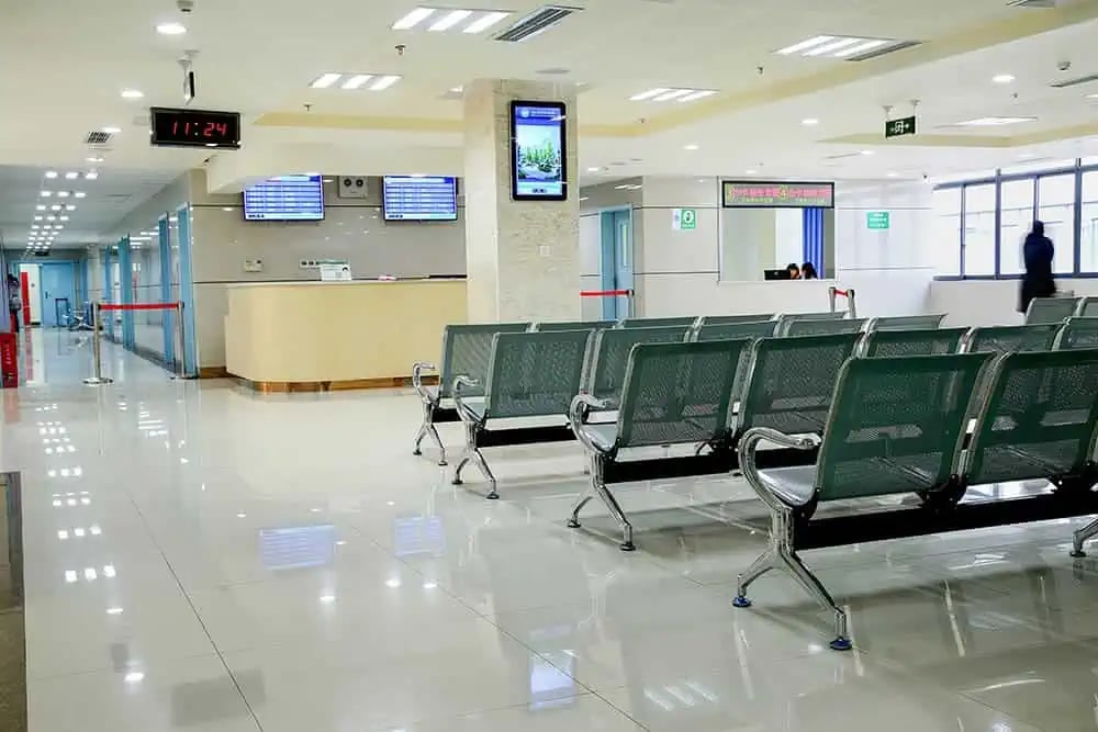 Corredor de hospital moderno, com recepção ao fundo e luz suave
