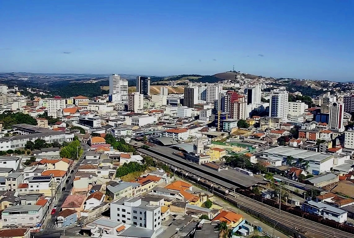 Vista aérea de Barbacena MG, com o centro urbano e serras ao fundo em dia claro