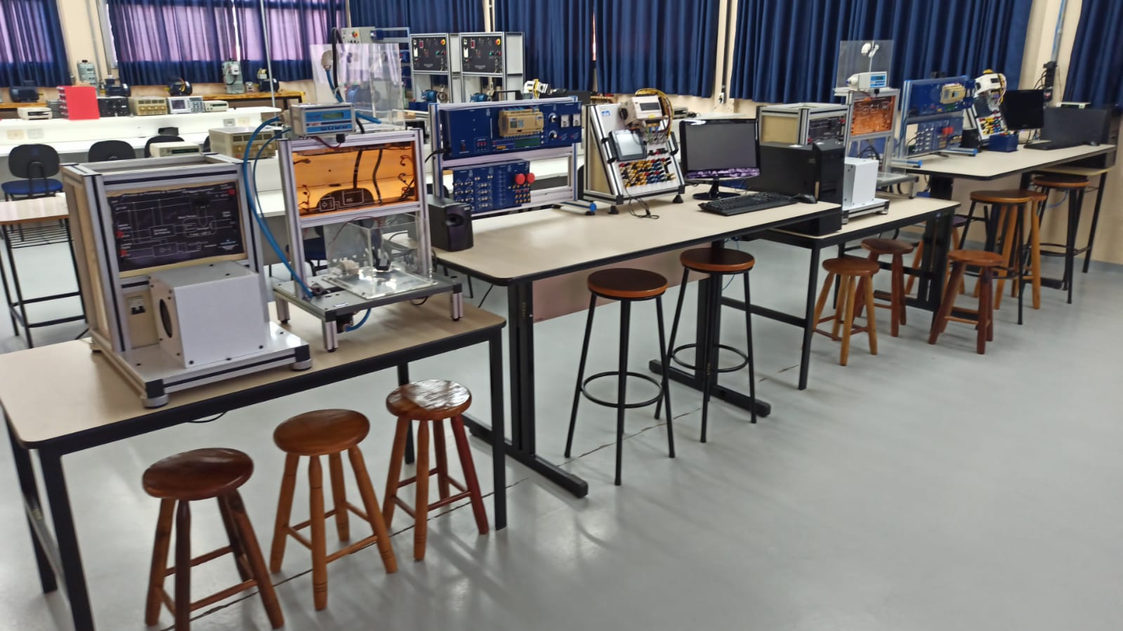 Laboratório de engenharia elétrica universitário, com equipamentos eletrônicos e placas de desenvolvimento sobre as bancadas