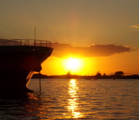 Skyline de Porto Alegre ao pôr do sol, com o Guaíba em primeiro plano.