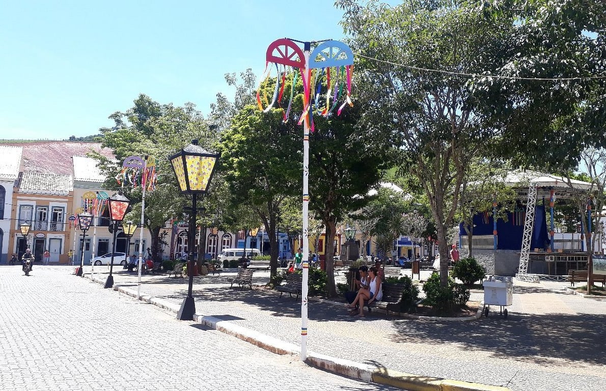 Cena urbana no interior de São Paulo, com praça arborizada e prédios baixos — referência visual ao cotidiano de municípios paulistas de médio porte