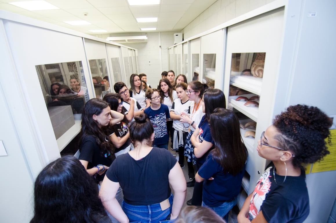 Interior do MAE-USP com vitrines e visitantes