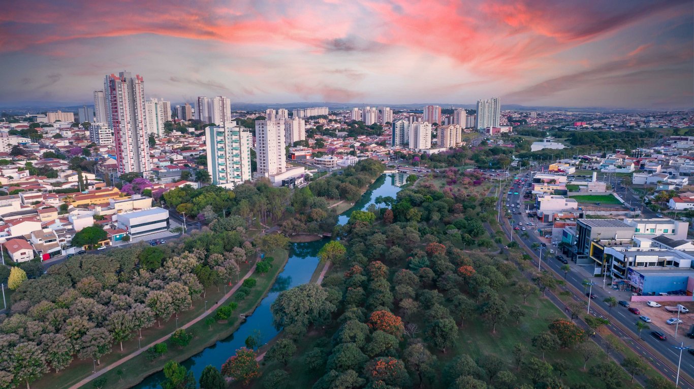 Vista panorâmica de Campinas ao entardecer, com prédios e áreas verdes