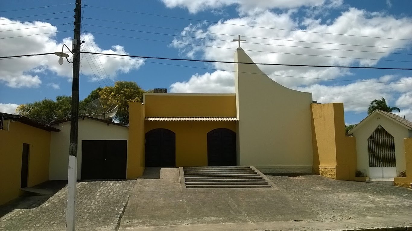 Igreja e área urbana de Cajueiro AL, céu azul e nuvens leves; patrimônio e cotidiano da cidade