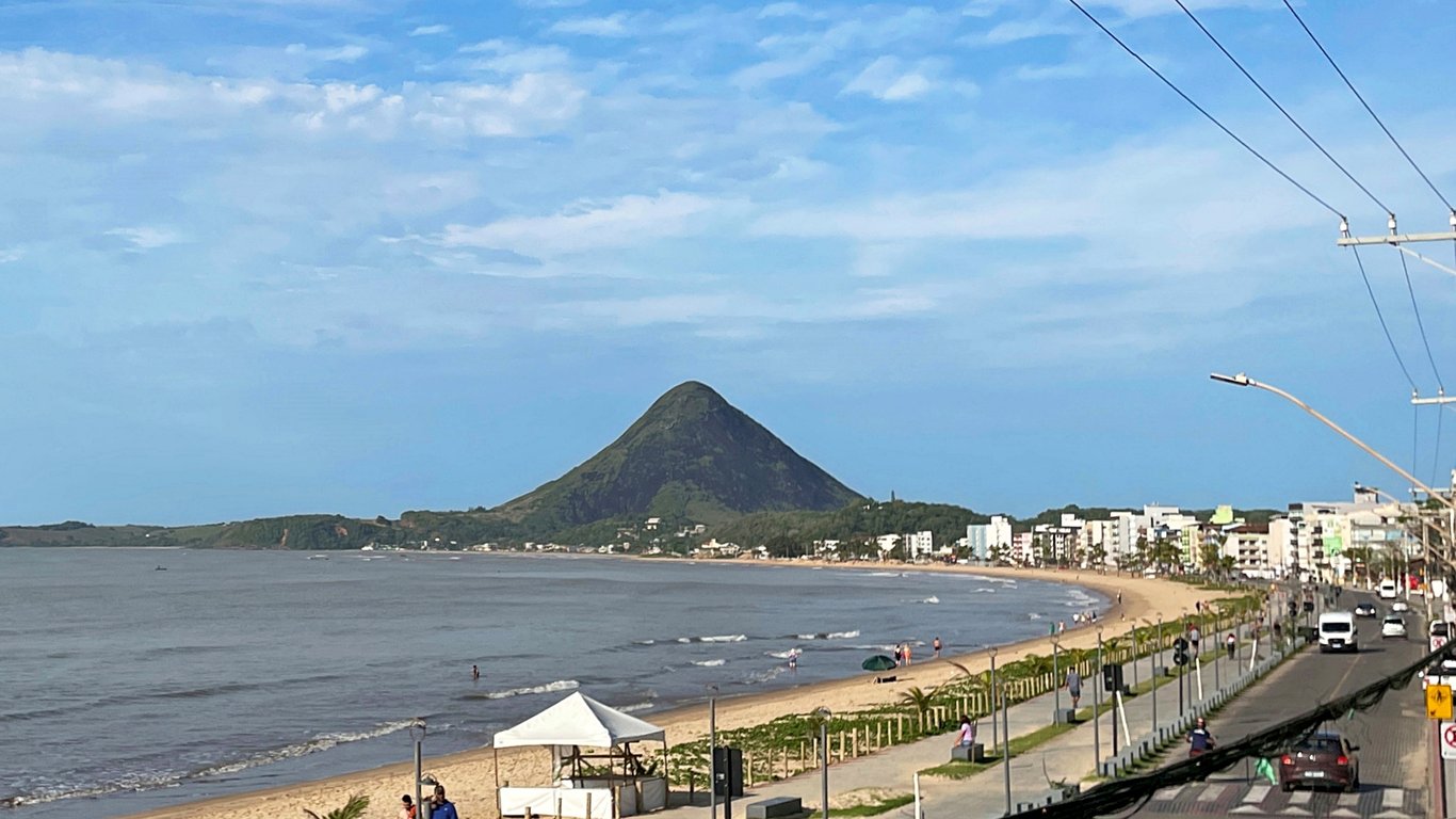 Vista aérea da praia de Piúma, mar calmo e faixa de areia ao longo da orla.