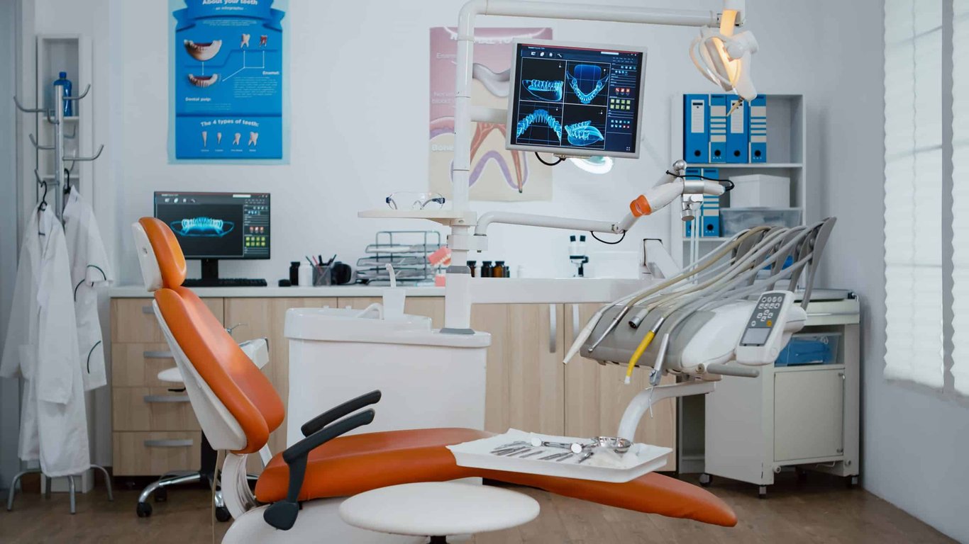 Foto de ambiente de clínica odontológica moderna com cadeira odontológica e instrumentos, bem iluminado e organizado, sem pessoas.