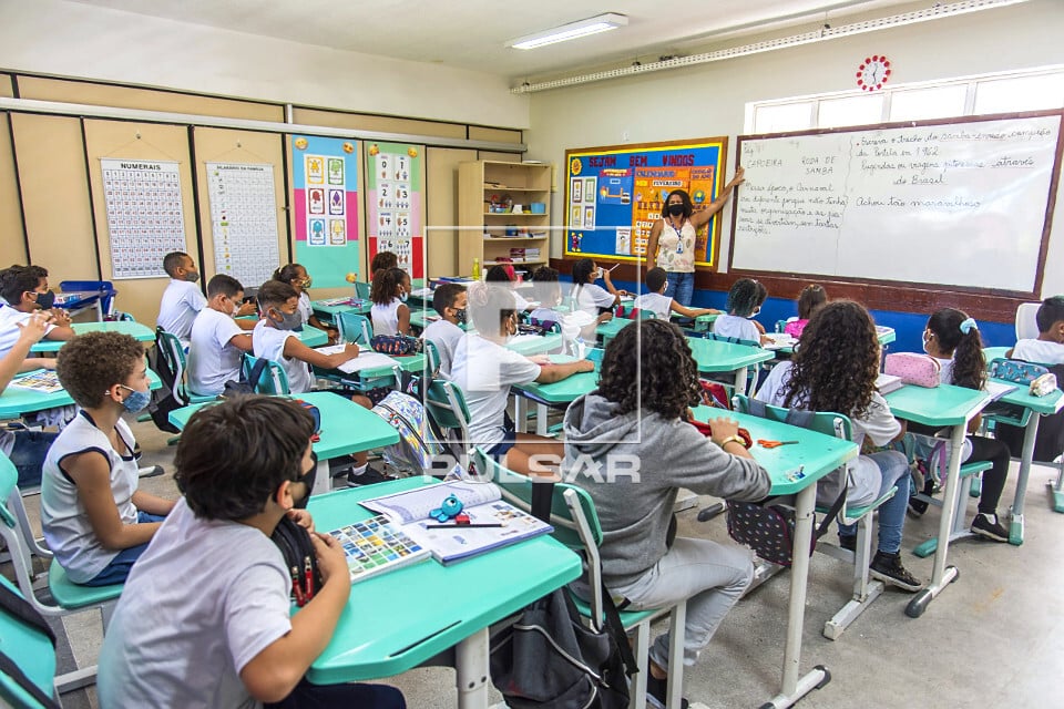 Sala de aula de escola pública com professor(a) e estudantes em atividade
