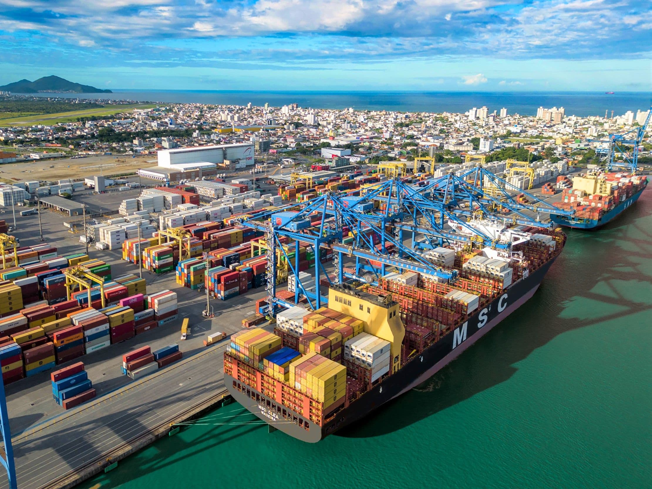 Vista aérea do terminal portuário de Navegantes com contêineres e guindastes ao entardecer