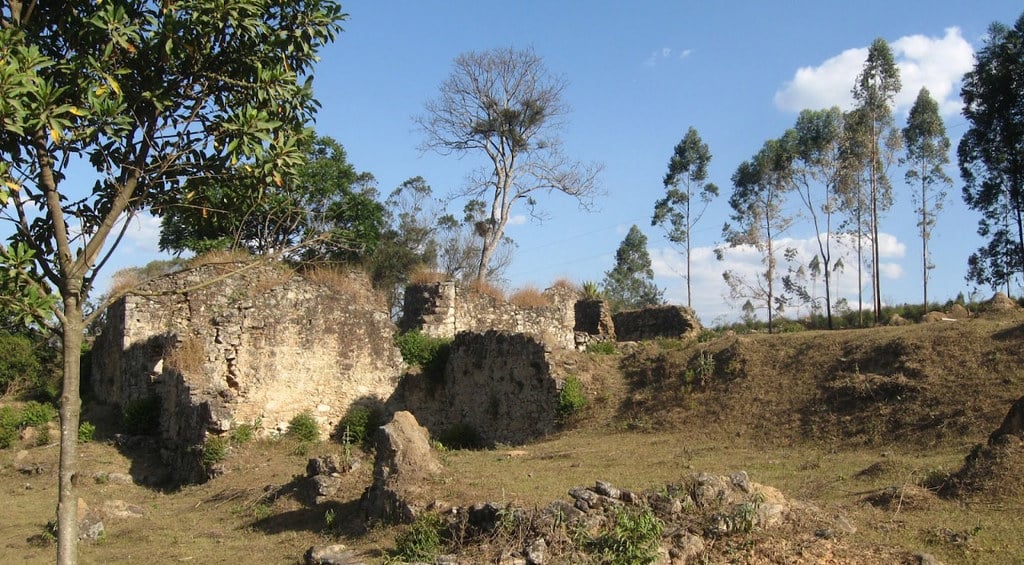 Vista rural de Entre Rios de Minas, Minas Gerais, com elementos arquitetônicos históricos numa paisagem natural.