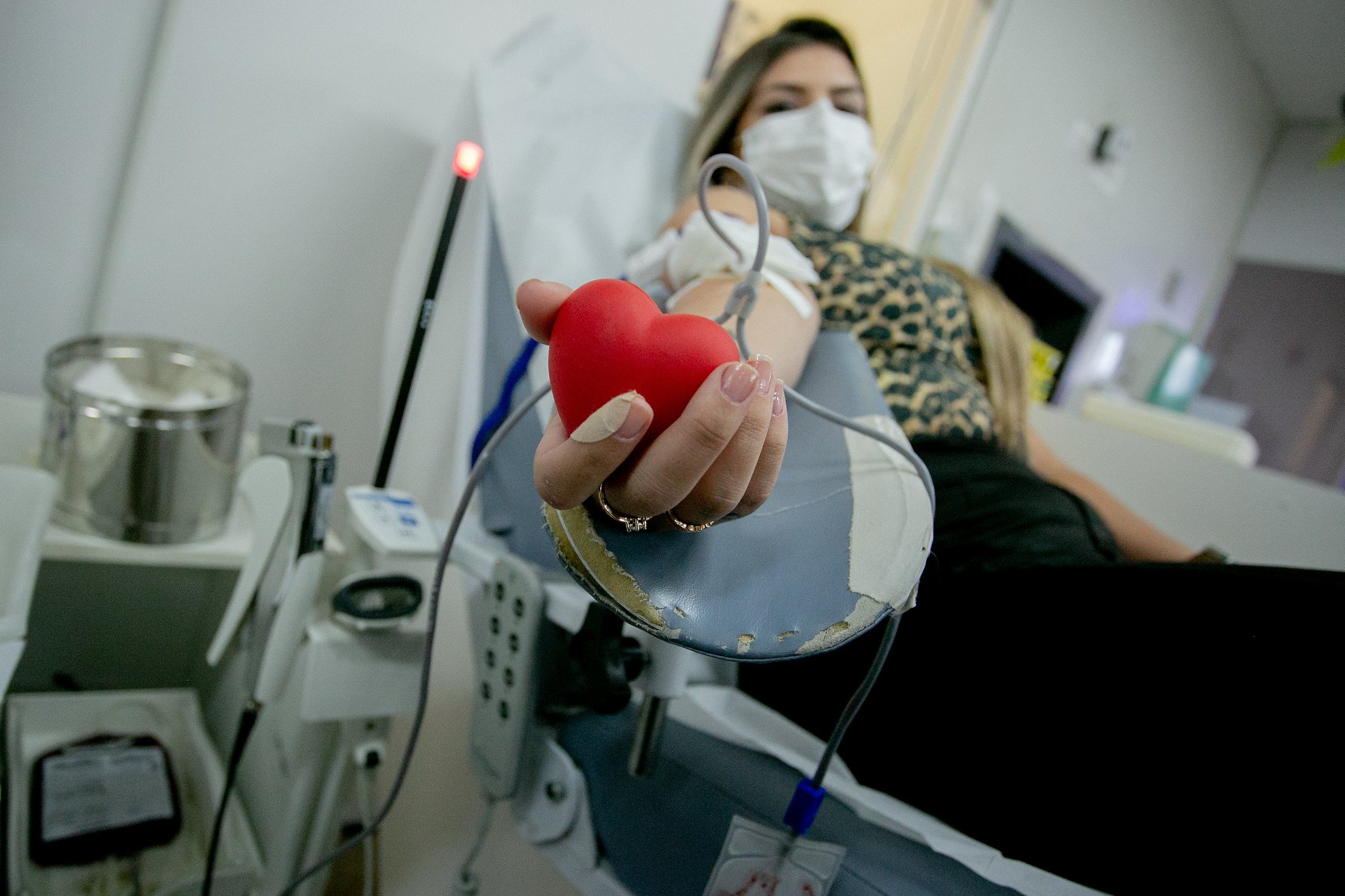 Profissional de saúde atendendo doadora de sangue em clínica moderna; ambiente claro, com equipamentos visíveis