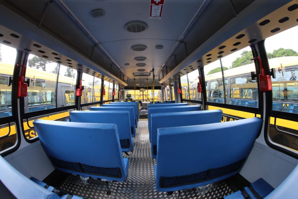 Interior de ônibus escolar com bancos e janelas, em perspectiva horizontal