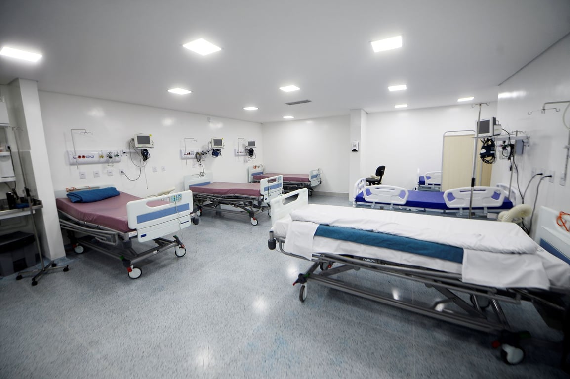 Corredor de hospital moderno, iluminado, com leitos organizados