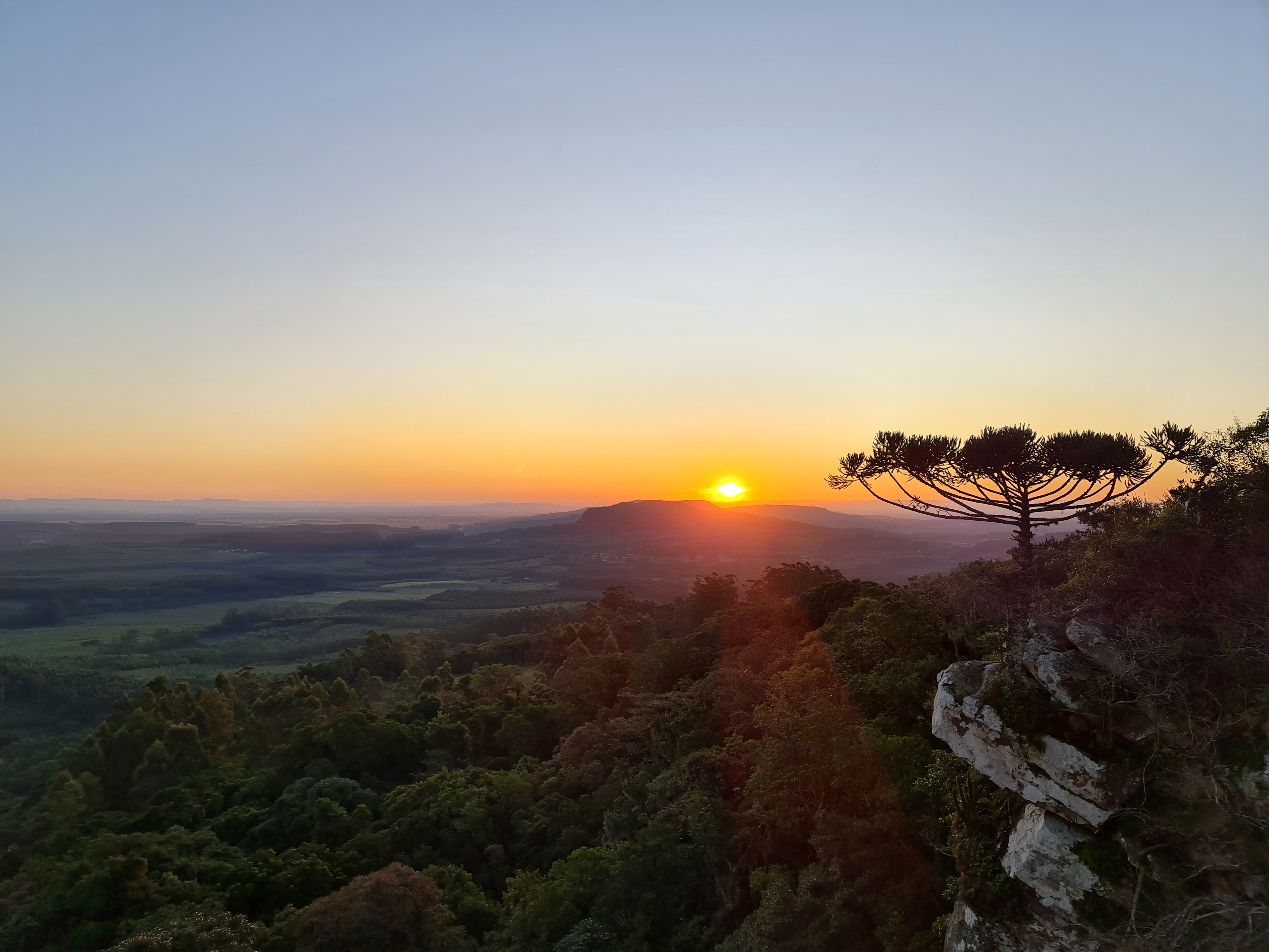 Vista do Vale do Taquari ao entardecer, com morros e vegetação nativa, em enquadramento panorâmico horizontal