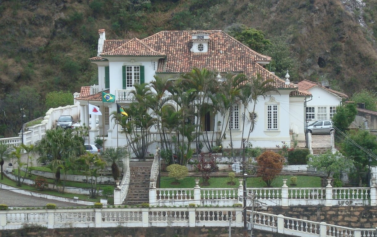 Fachada de prédio da UFOP em ambiente acadêmico, com vegetação ao redor