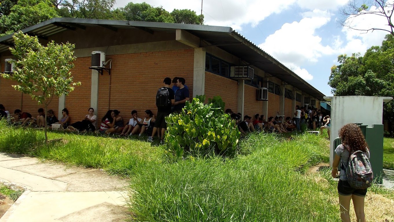 Campus da Unesp em Bauru ao entardecer, com estudantes circulando em área verde