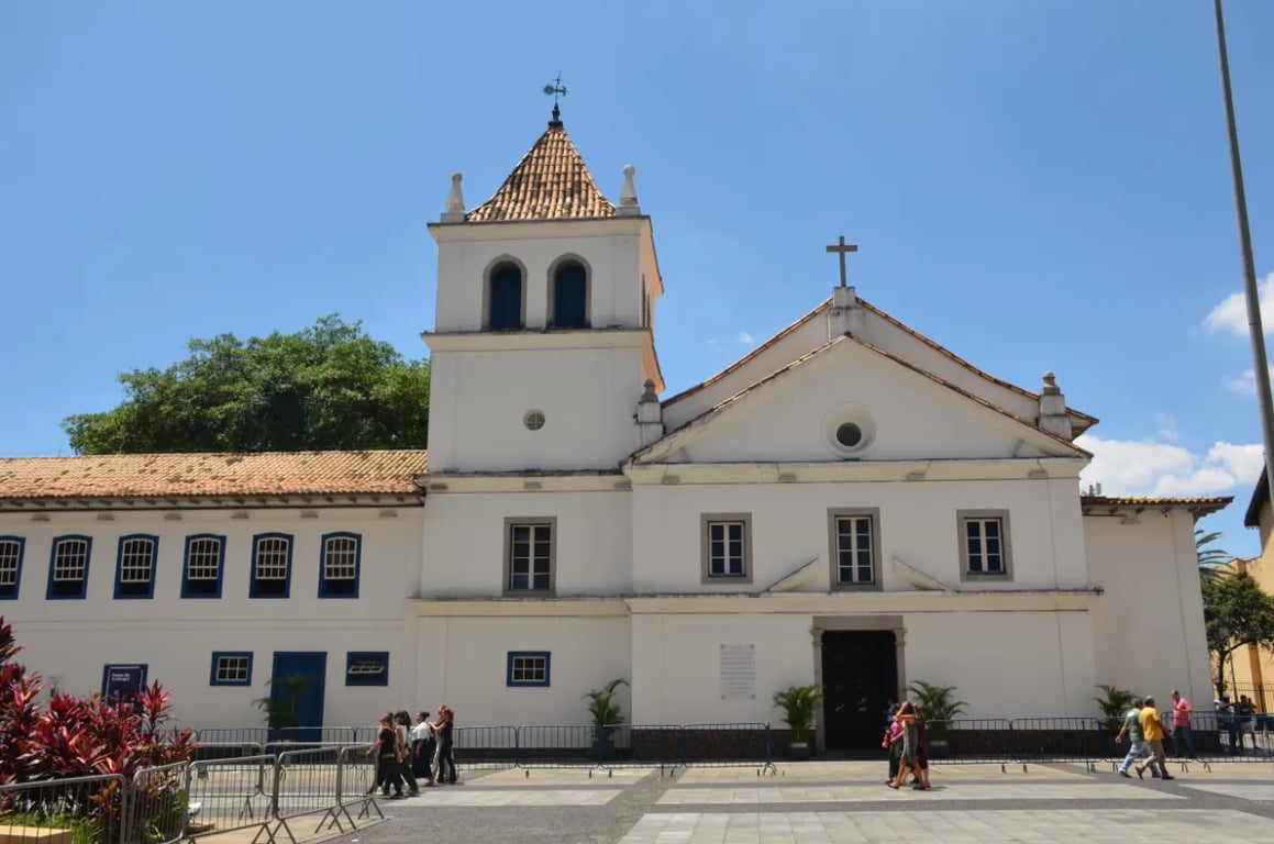 Praça e igreja em cidade do interior de SP, céu claro e movimento de pedestres
